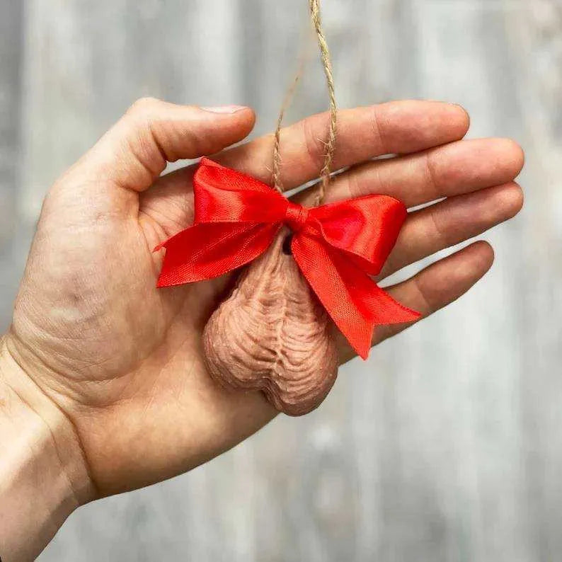 a person's hand holding a red ribbon ornament