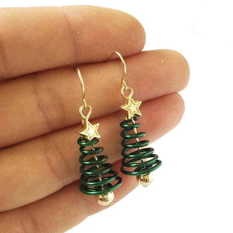 a hand holding a pair of christmas tree earrings