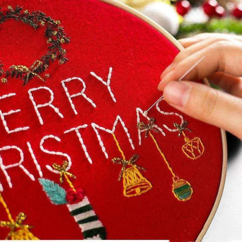 a person is stitching a merry christmas sign on a red pillow