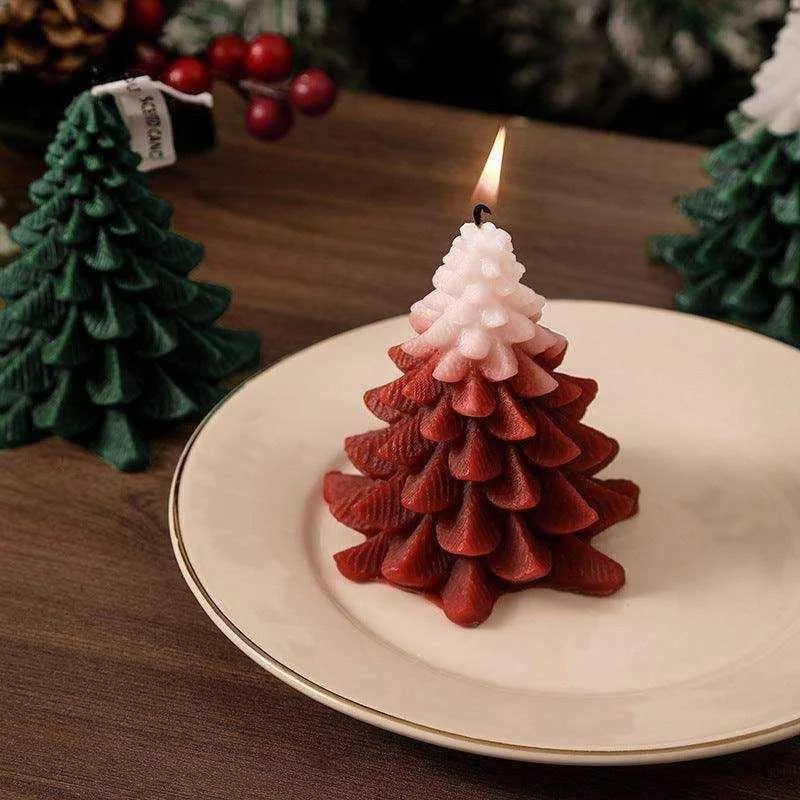 a small red christmas tree candle on a white plate